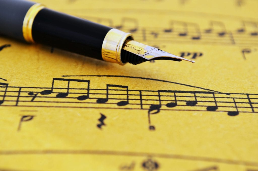 Fountain pen on music sheet to illustrate best background music for writing content