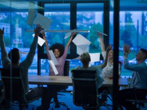 multiethnic Group of young business people throwing documents and looking happy while celebrating success at the office to illustrate Marketing During Recessions Time For Bold Moves, Creativity