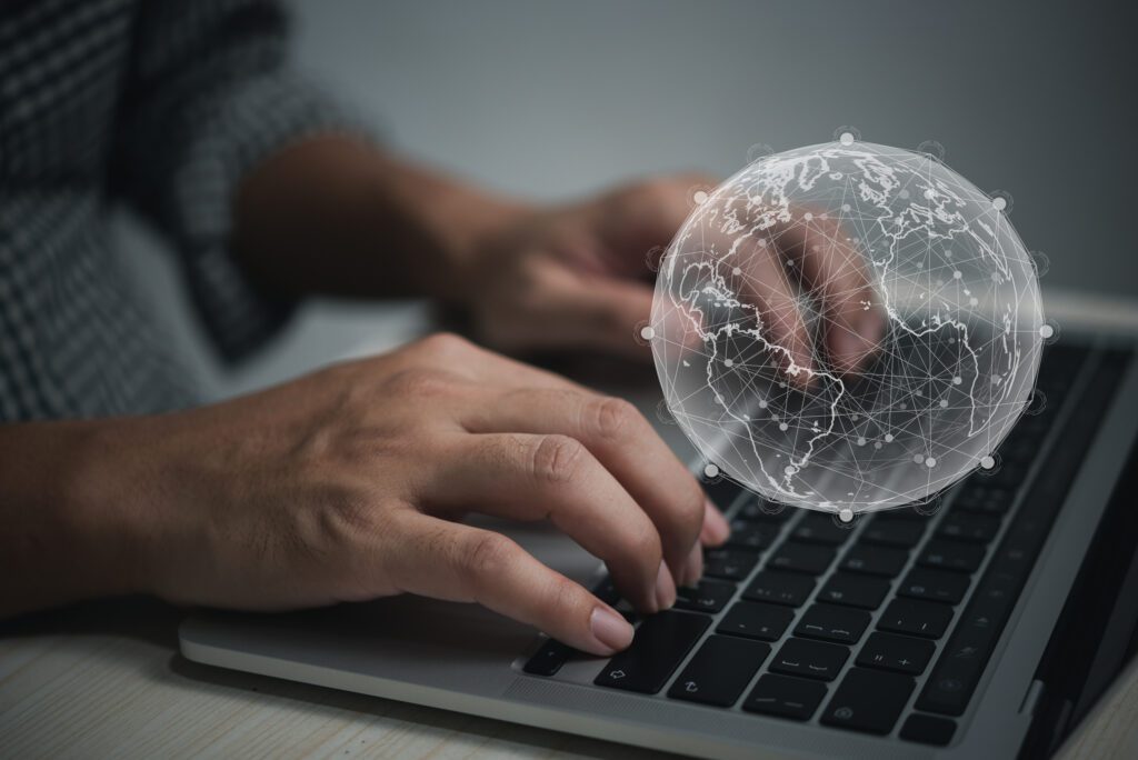 Hands type on a laptop while a digital image of the world in white floats above the keyboard to illustrate State of Search Highlighting Highlights of Semrush’s Report