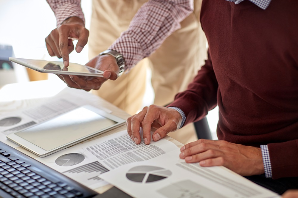 Marketing professionals with a tablet, pc and charts at an office.