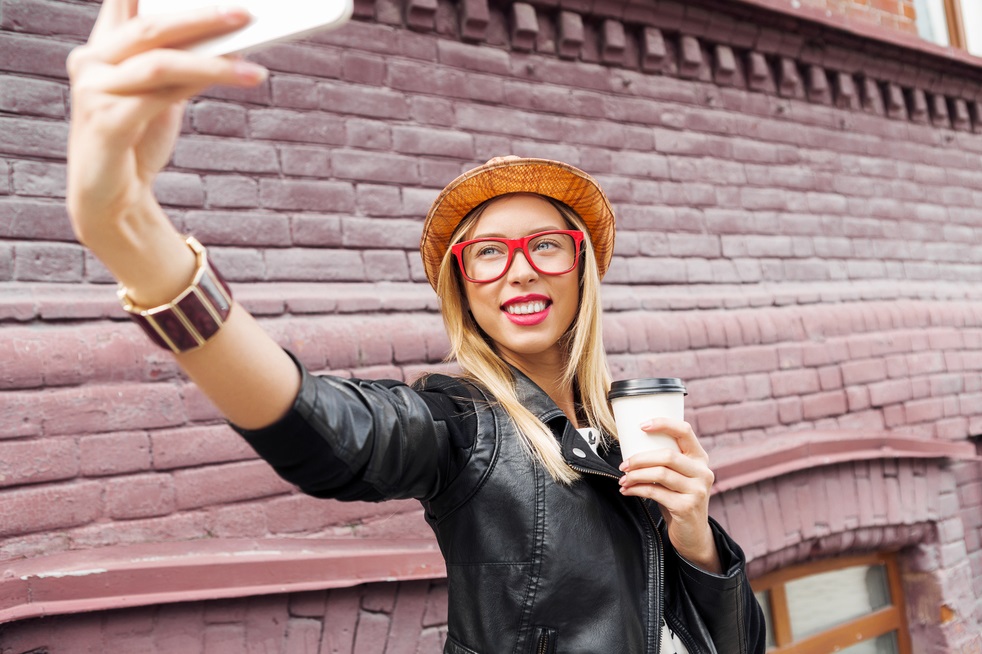 Woman taking selfie with smart phone in street of a city.