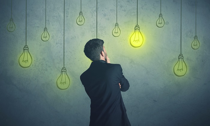 man standing in front of background graphic of lightbulb lit up 